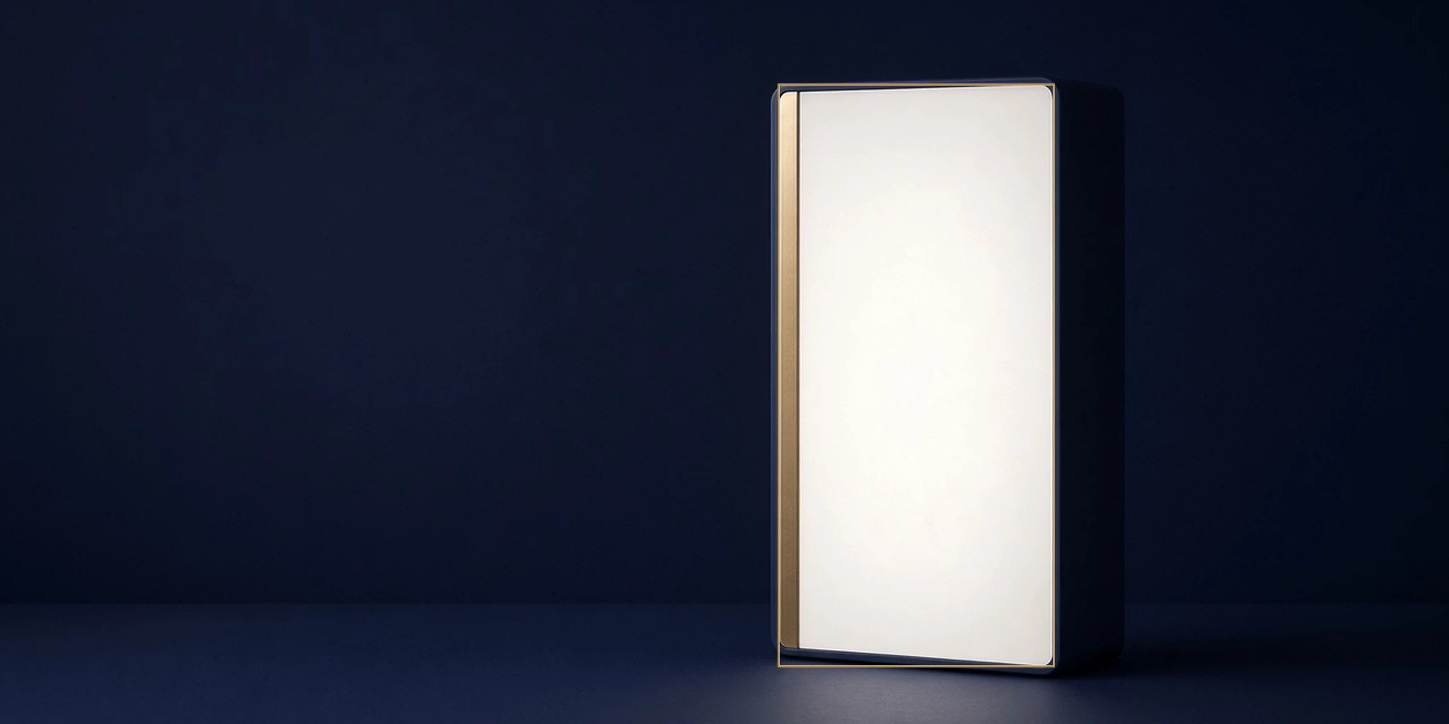 Rectangular light therapy box glowing on a navy desk with a thin gold morning stripe and thin gold rim.